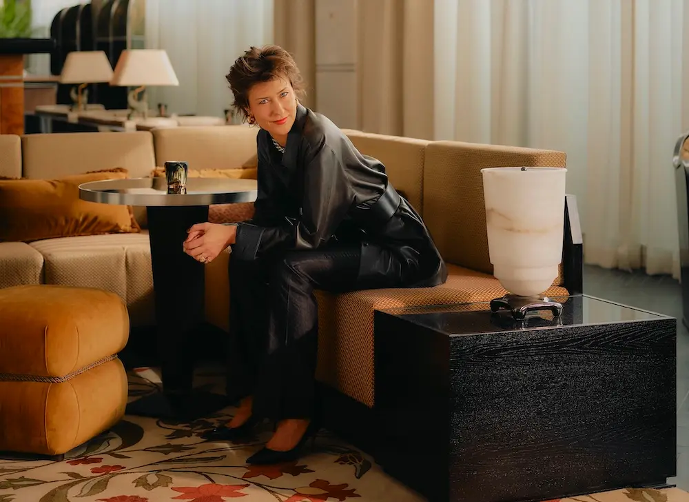 Kreativer Kopf vom Hotel The Dean Munich: Tatjana von Stein in ihrer selbst gestalteten Lobby auf gelben Sofa