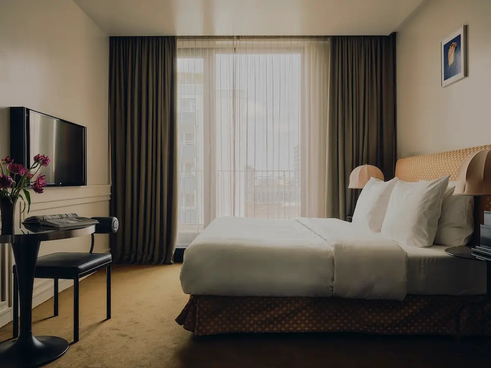 Deluxe Guest Room im Hotel The Dean in München mit grünen Vorhängen und gelbem Teppichboden