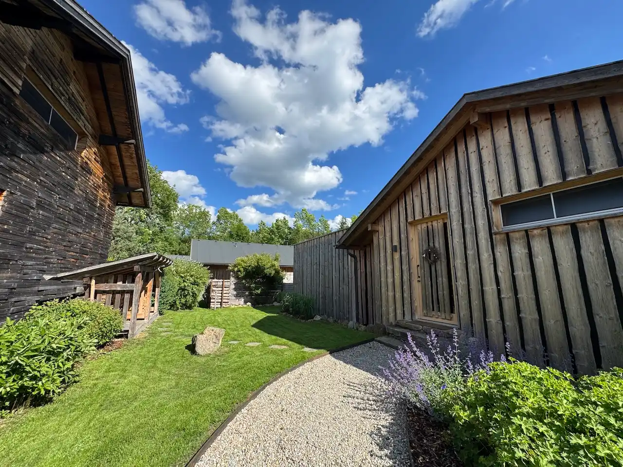FORSTGUT Chaletdorf: Zwei der Holzchalets, grüner Rasen