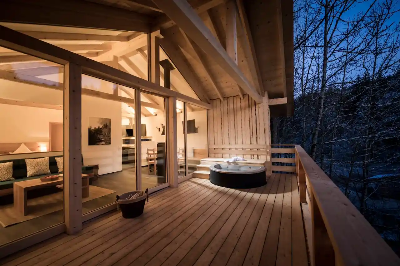 Terrasse aus Holz mit Blick in ein Holzchalet bei Abendlicht
