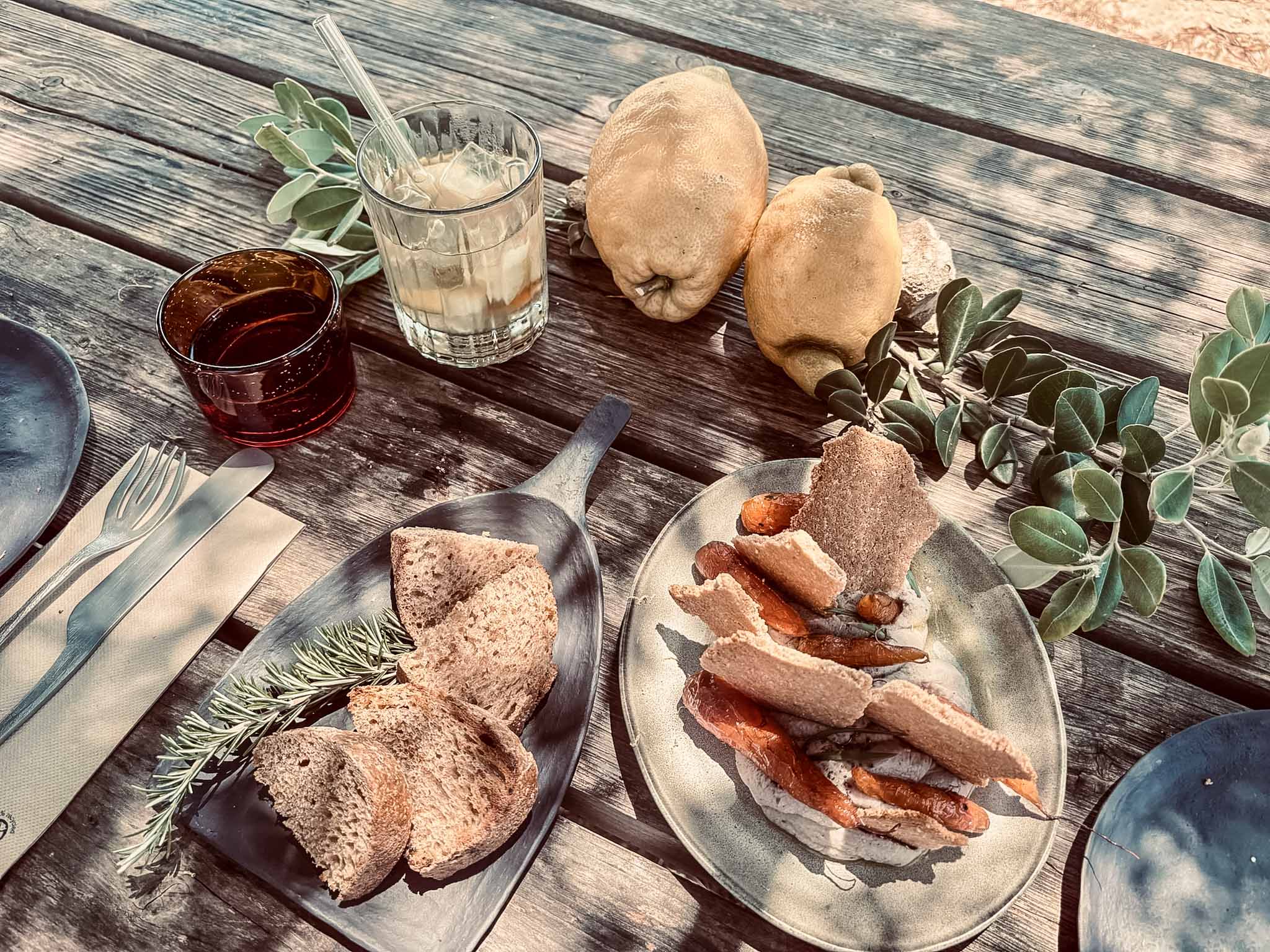 Frisch zubereitetes Lunch auf dem Holztisch im Son Blanc Farmhouse mit rustikalem Landbrot, Rosmarin, Zitronen und Erfrischungsgetränken.