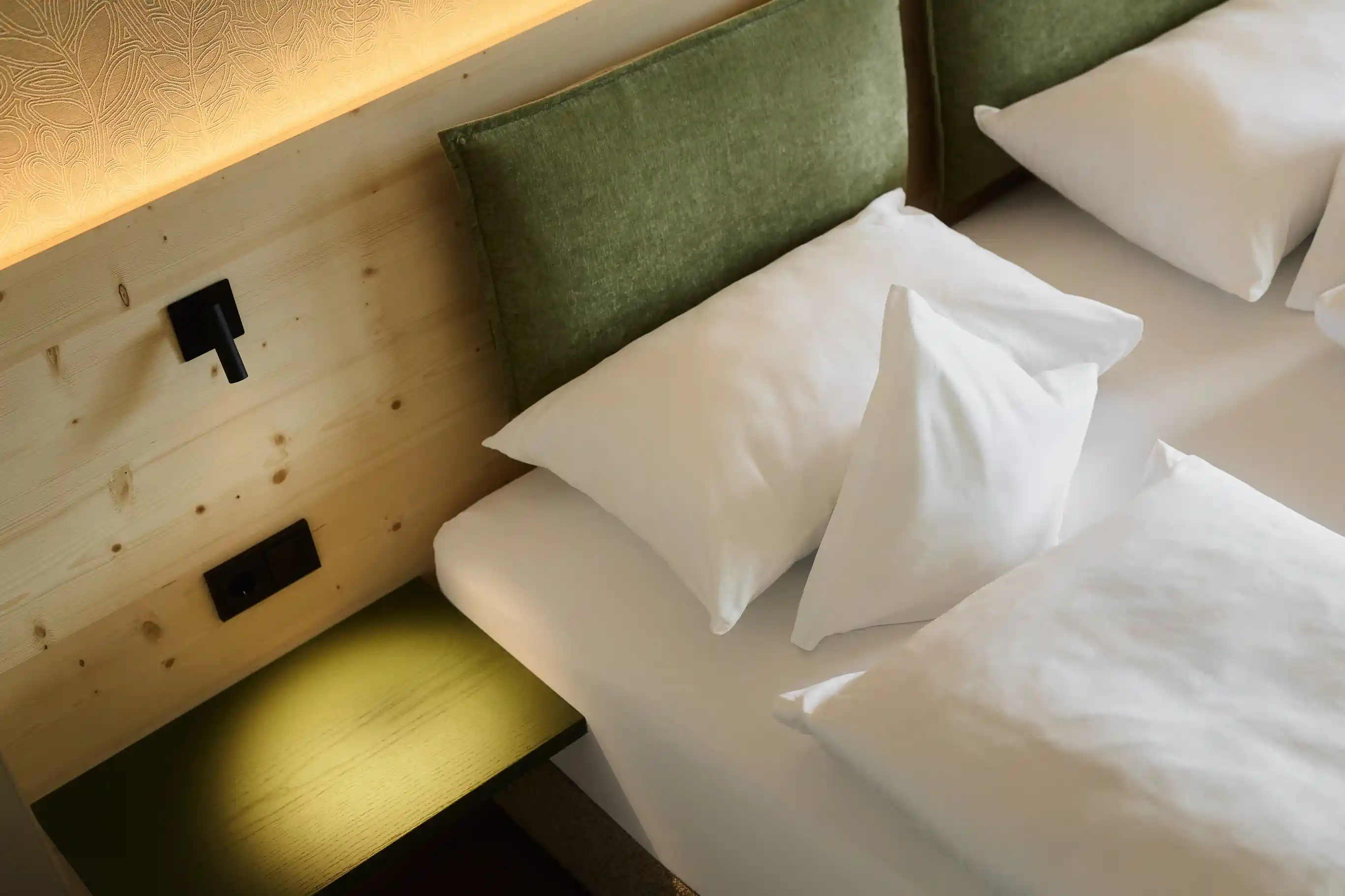 Schlafen im Hotel AUI: Weiße Bettlaken, Holz und grüne Details