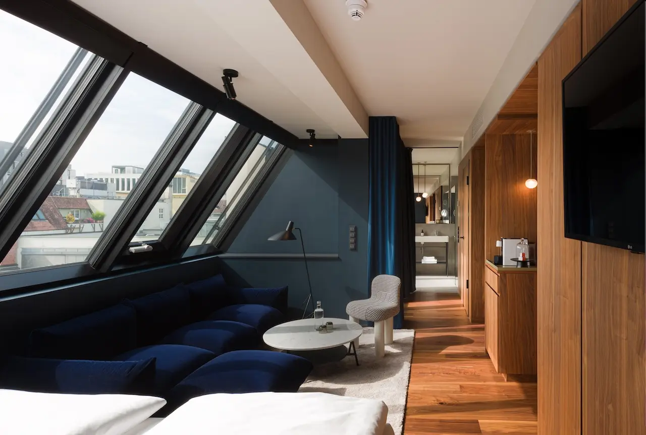 Zimmer im Dachgeschoss des EMILU Hotels mit Dachfenstern und blauer Wand