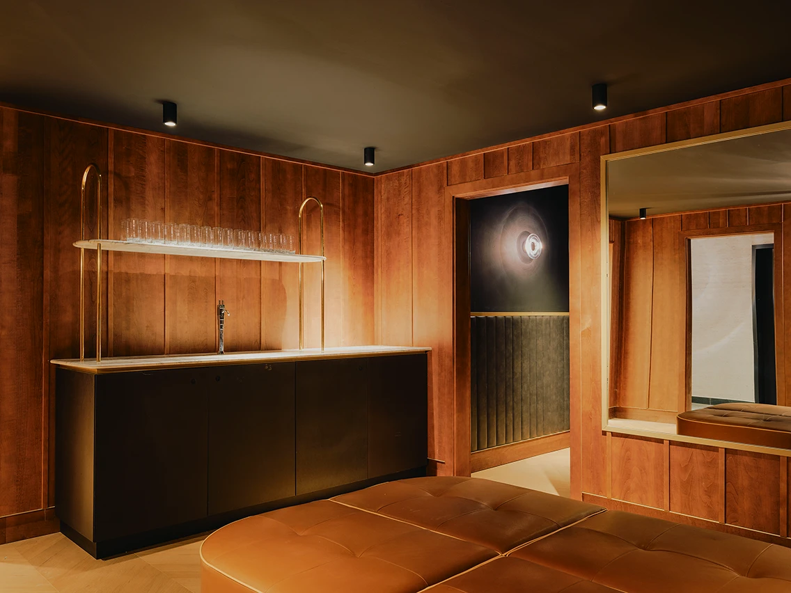 Holzverkleideter Erfrischungsbereich mit Ledersitzbank und Wasserstation im Gym-Bereich des Hotels The Dean an der Landsberger Straße München