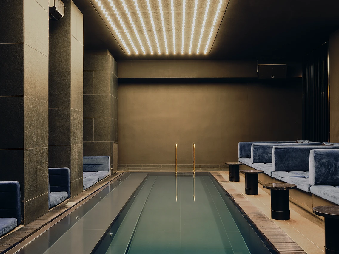 Intim beleuchtetes Indoor-Pool-Entspannungsbecken mit Samt-Sitznischen im Spa-Bereich des Designhotels The Dean München
