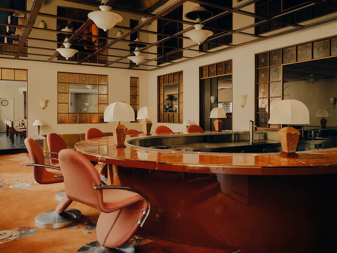 Eklektische Hotelbar mit geschwungener roter Theke, samtenen Barhockern und opulenter Deckenverkleidung im Restaurant Ibasho im The Dean München