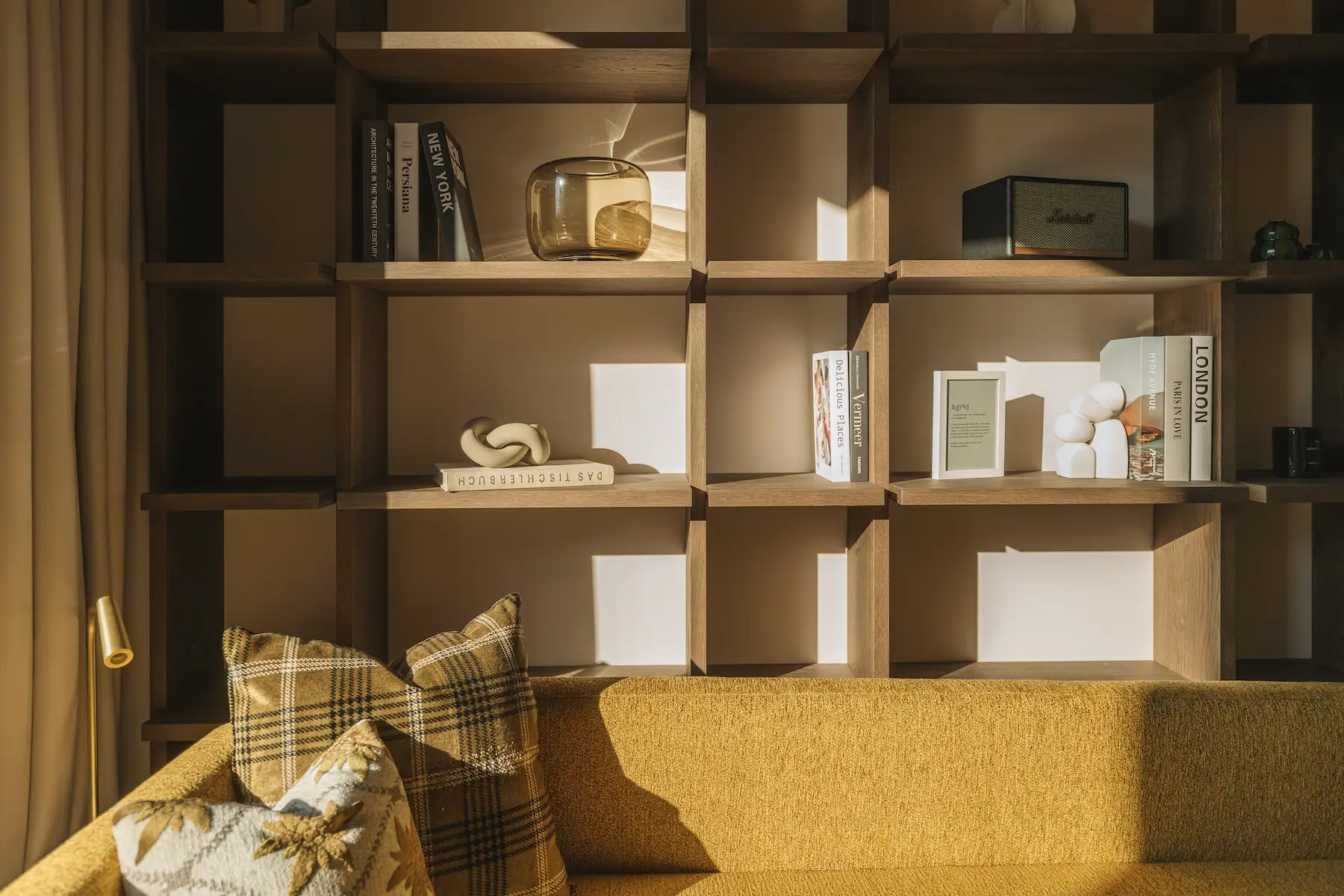 Agrad Chalets: Regal hinter gelbem Sofa im Sonnenlicht || © Andreas Jacob