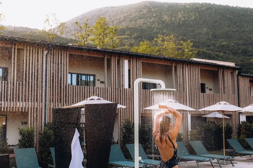 Frau unter Outdoor-Dusche in den Agrad Chalets im Chiemgau || © Formgestalter