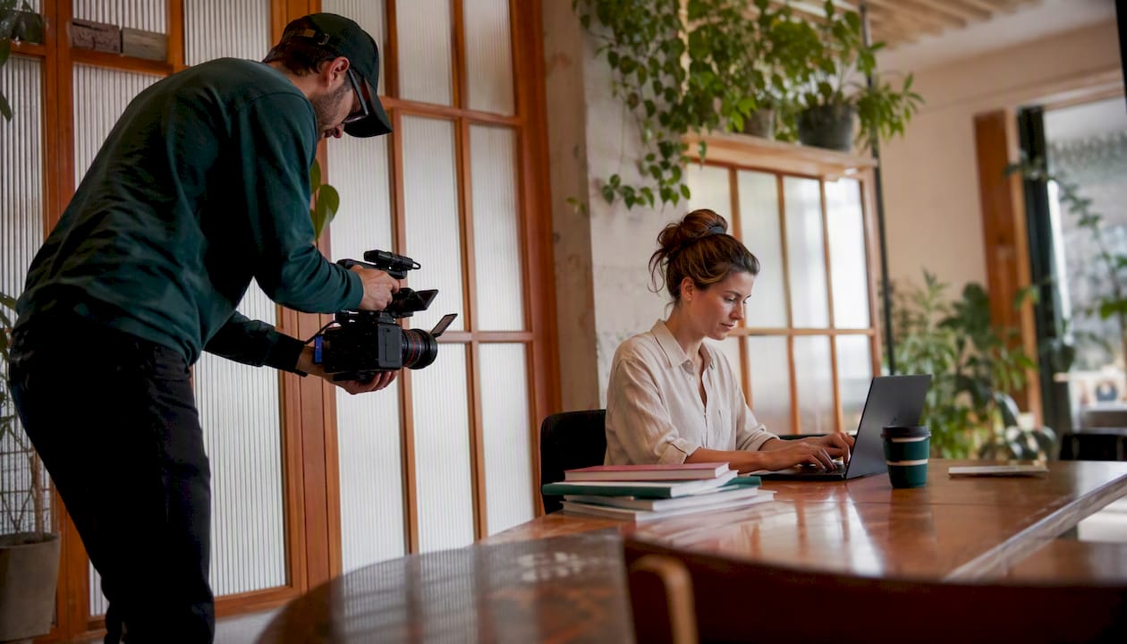 Videographer filming employee at office