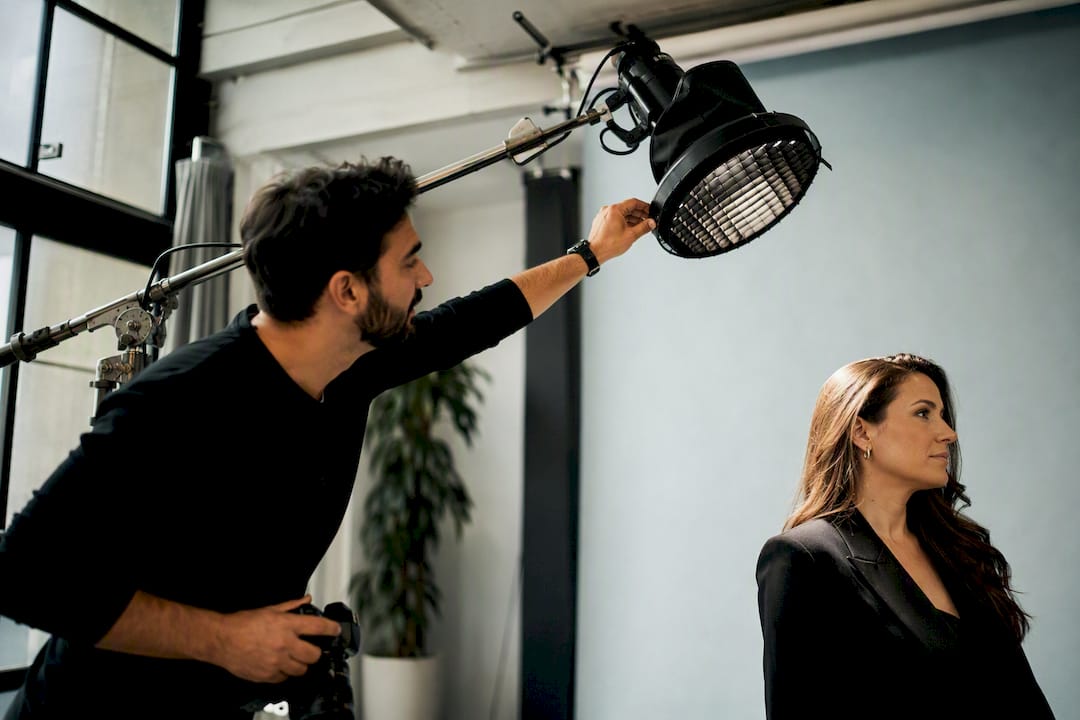 Photographer adjusting gridded rim light on boom