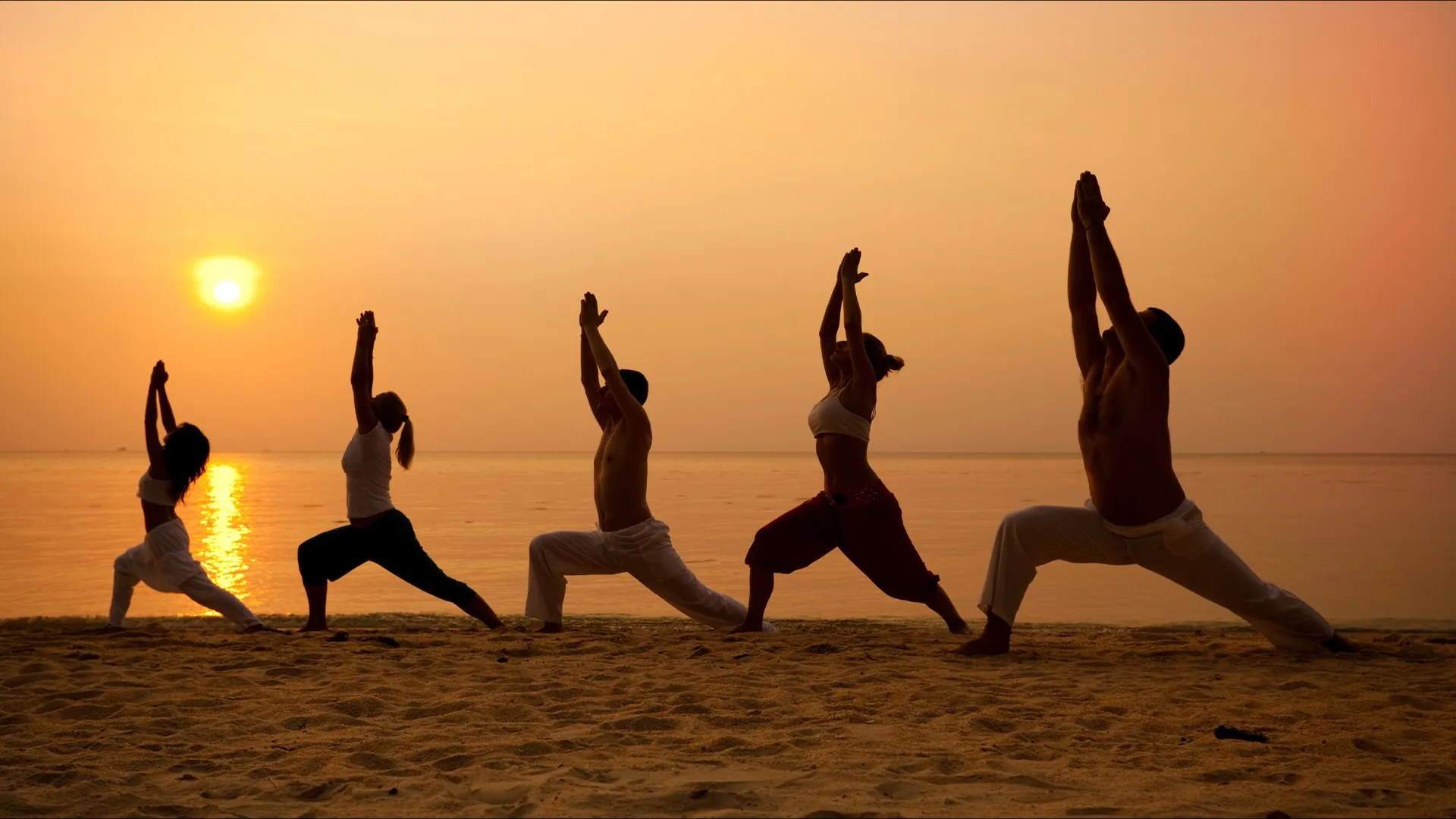 People doing yoga on the beach
