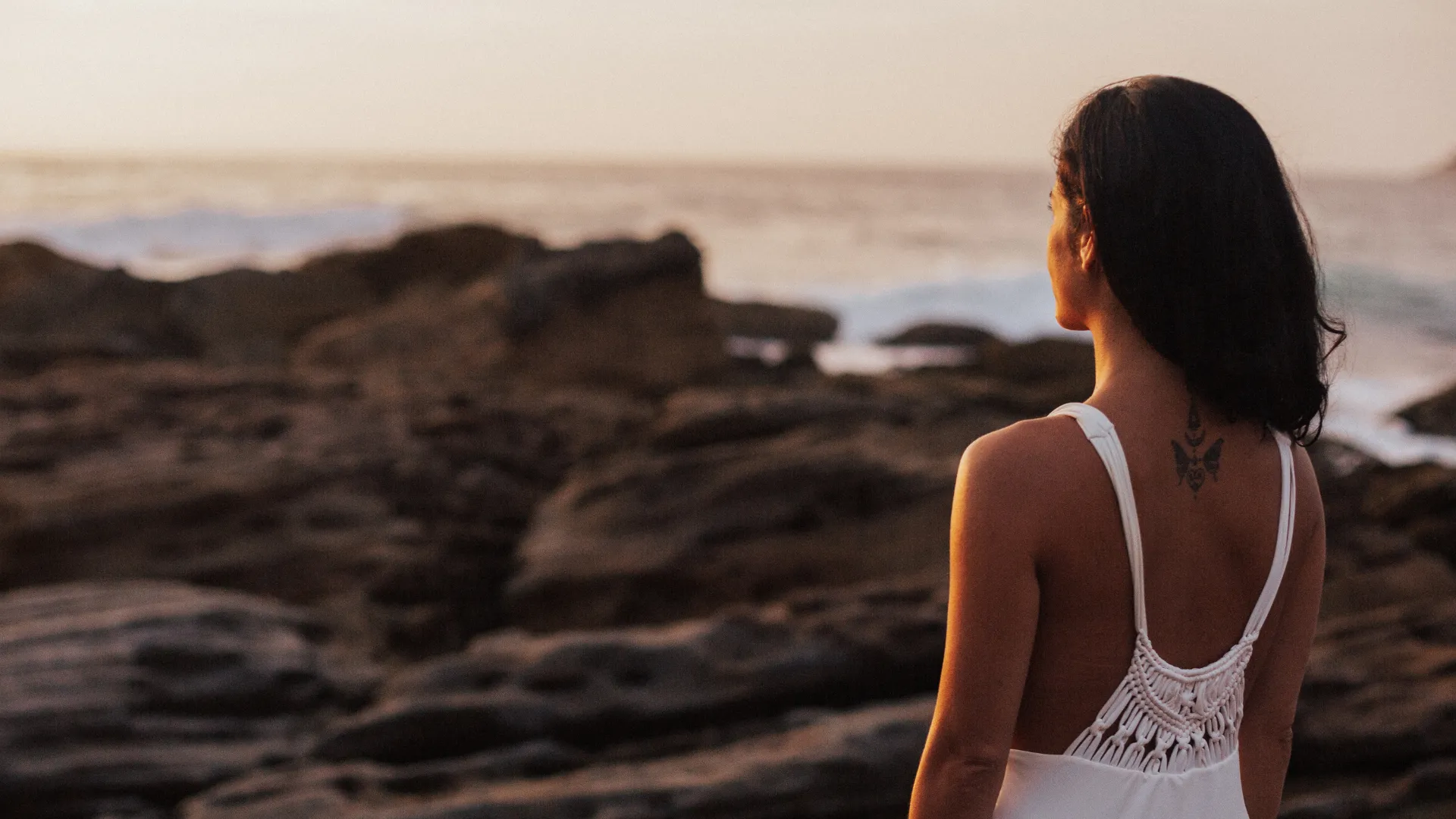 Woman standing on rocks next to the ocean