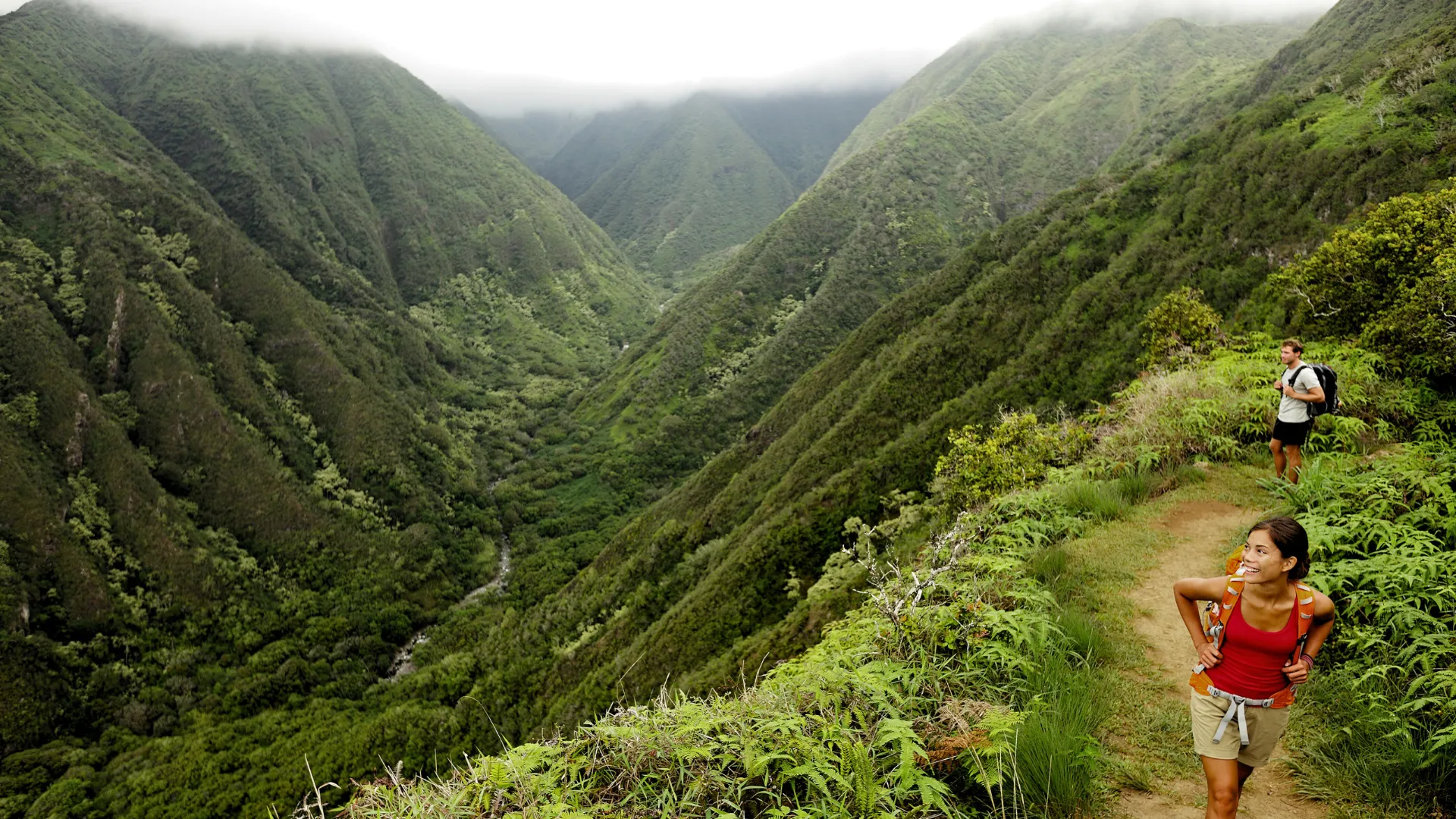 Two people hiking through a valley in Hawaii
