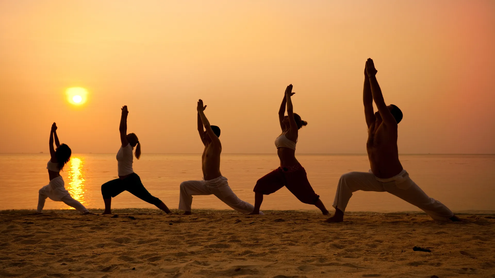 People doing yoga on the beach