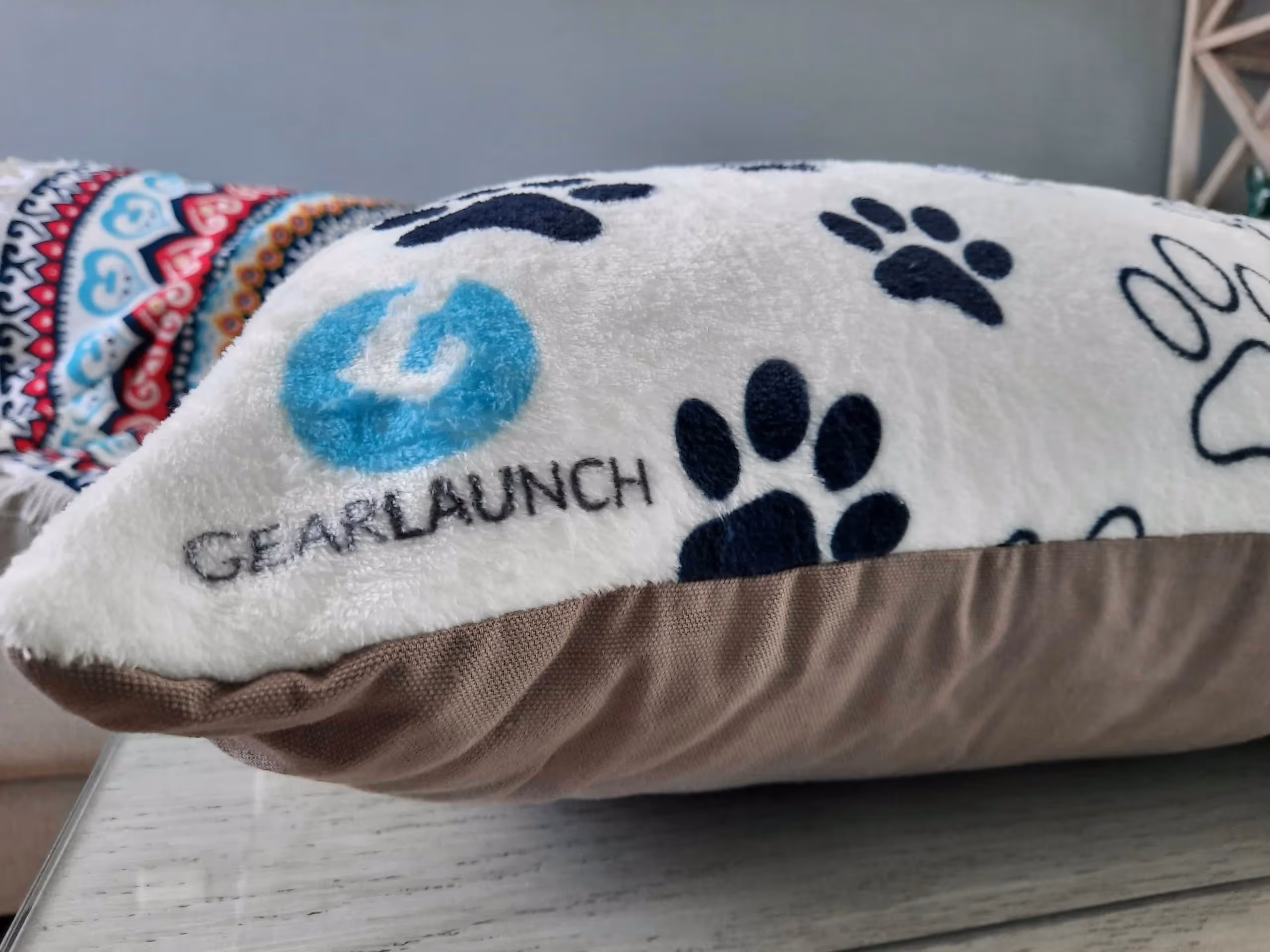 Close up of indoor pet bed, white background with black paw prints and GearLaunch Logo