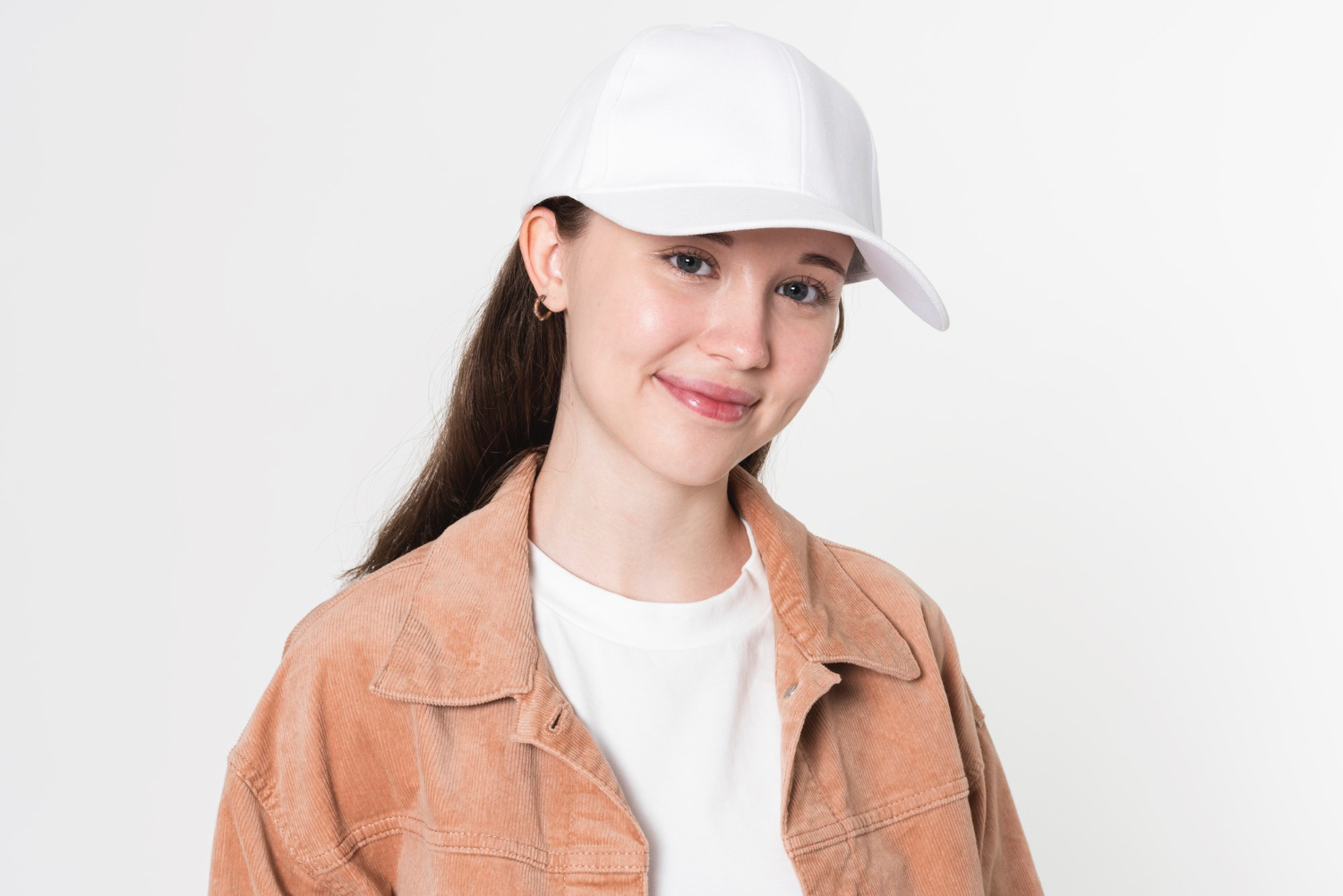 Smiling young woman wearing a plain white baseball-style hat and beige corduroy jacket — ideal lifestyle mockup for custom trucker or dad hat product listings.