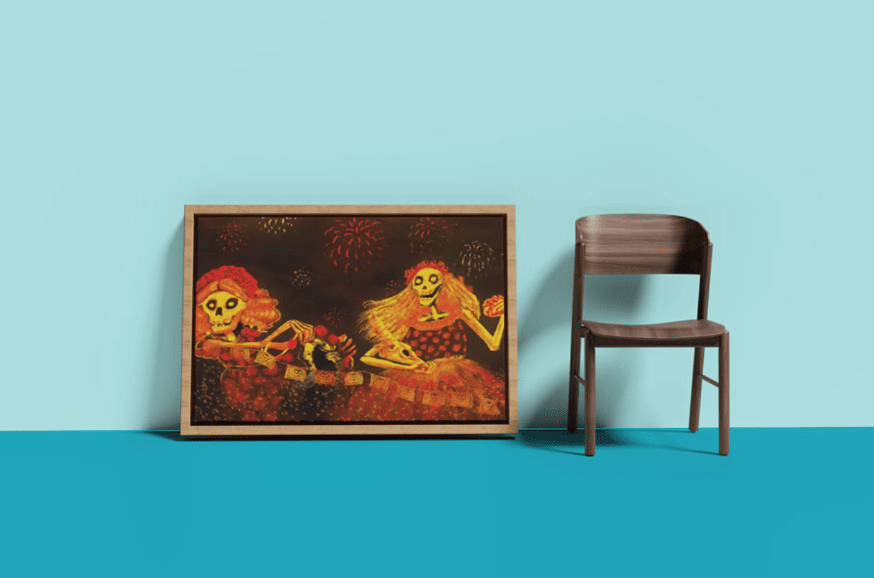 Framed wall art featuring colorful Día de los Muertos-style skeleton characters with fireworks, leaning against a pastel blue wall beside a wooden chair — vibrant mockup for seasonal or cultural-themed canvas prints.