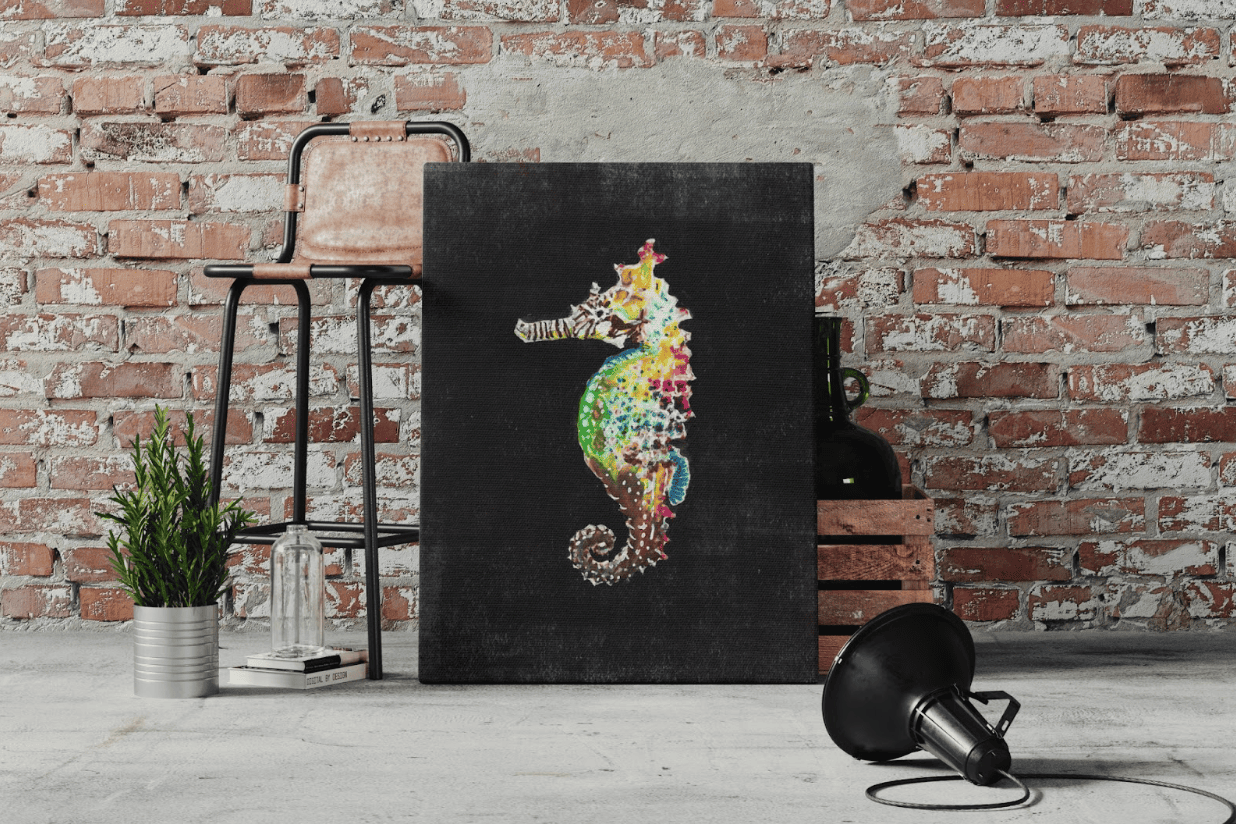 Artistic canvas print featuring a colorful seahorse on a black background, styled against an exposed brick wall with industrial decor — modern wall art mockup perfect for lofts, studios, or coastal-inspired interiors.