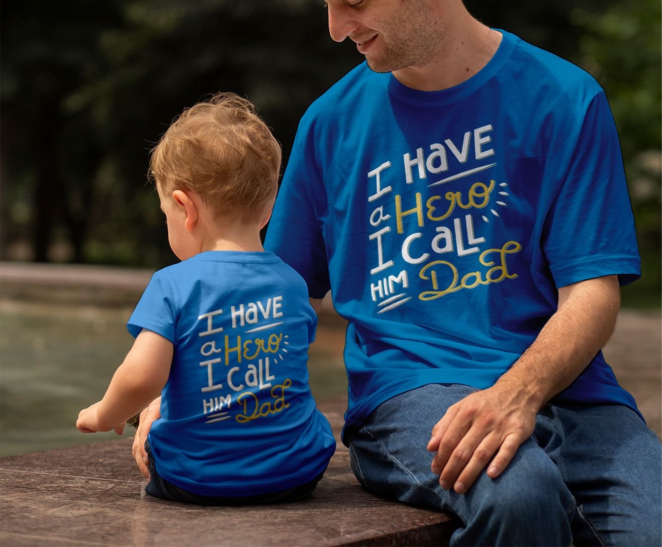 Father and son wearing matching blue T-shirts with ‘I Have a Hero I Call Him Dad’ design – custom family apparel for print-on-demand sellers