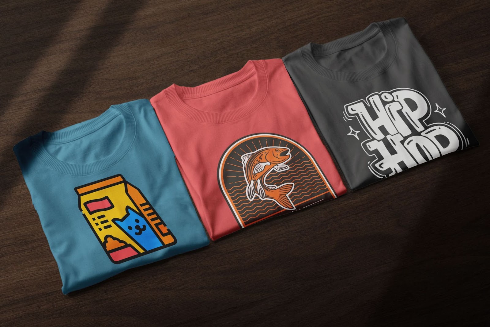 Three folded graphic T-shirts with cat milk carton, fish illustration, and hip hop typography – trendy custom designs for print-on-demand