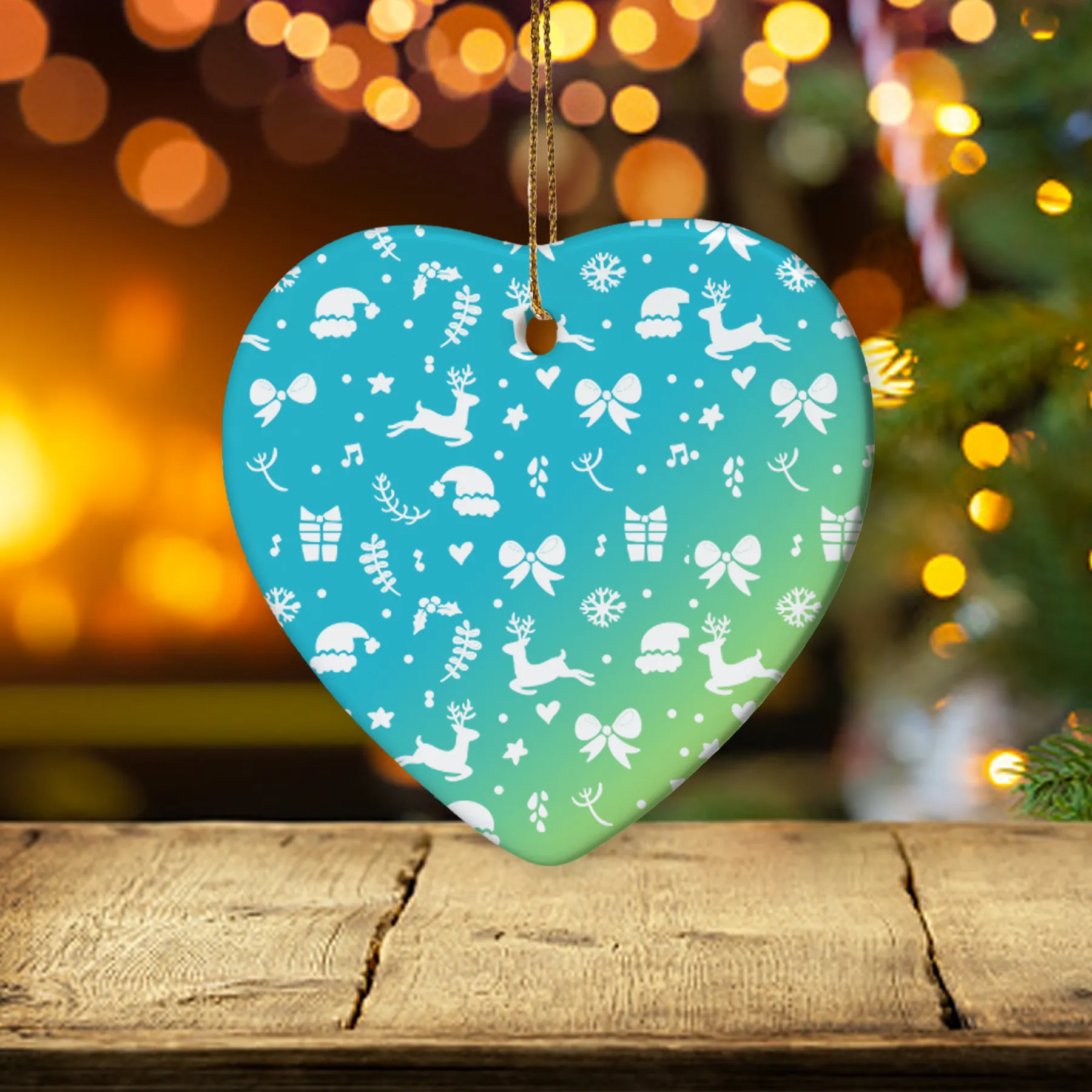 Heart-shaped ceramic ornament featuring playful holiday patterns like reindeer, snowflakes, and gifts, hanging in front of a Christmas tree with twinkling lights.