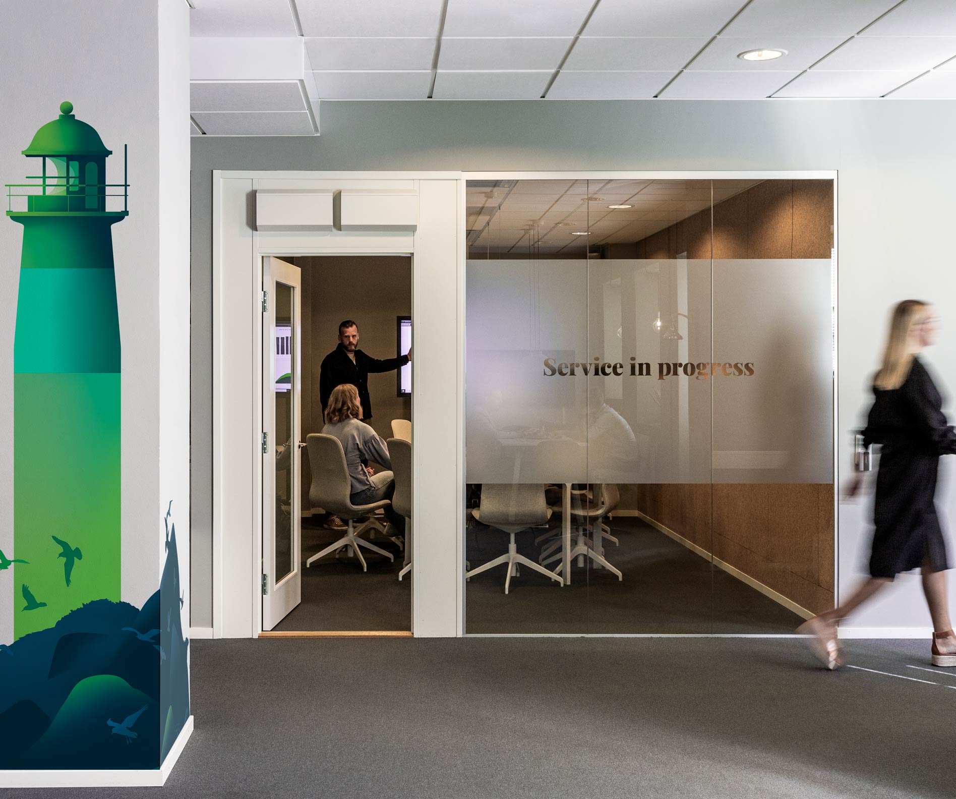 Office entrance with a green lighthouse mural and a person walking past
