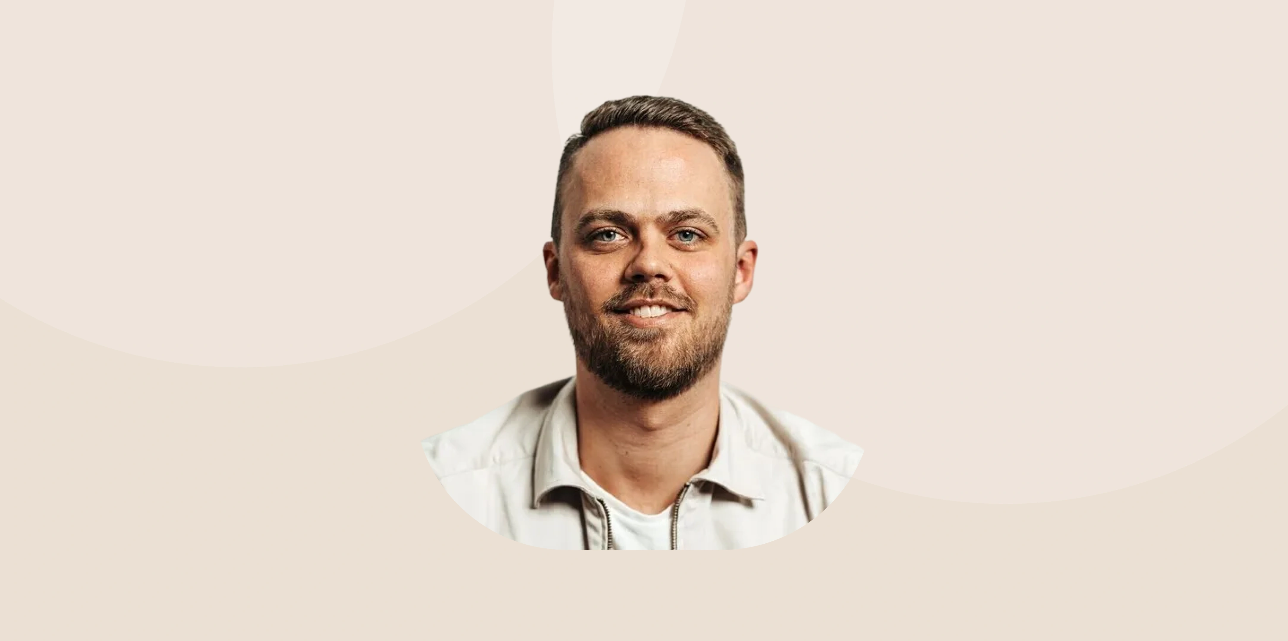 Smiling man with short hair in a light open-collar shirt, portrait on a beige background