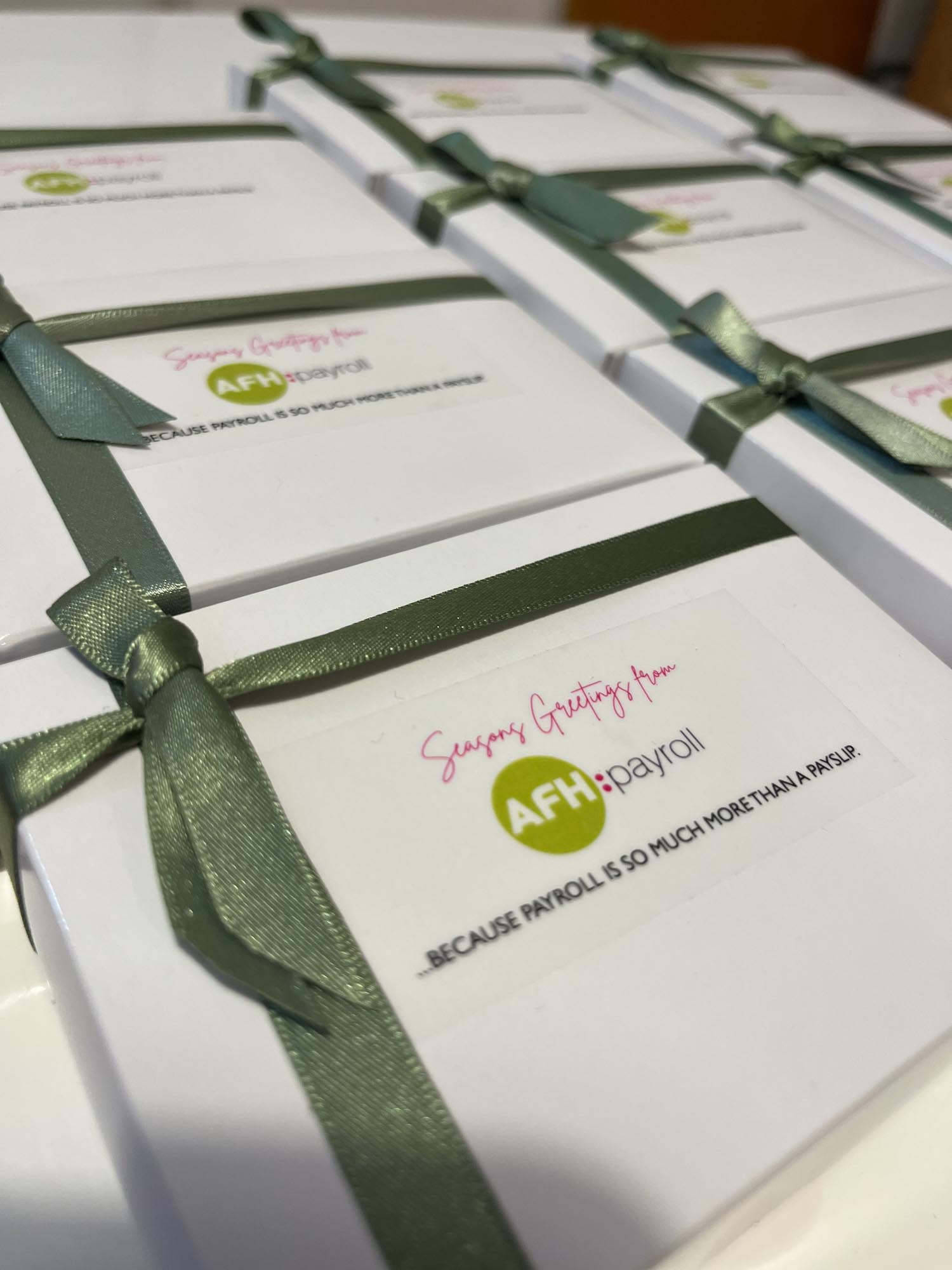 Several white gift boxes with green ribbons, labeled with "Season's Greetings from AFH:payroll."