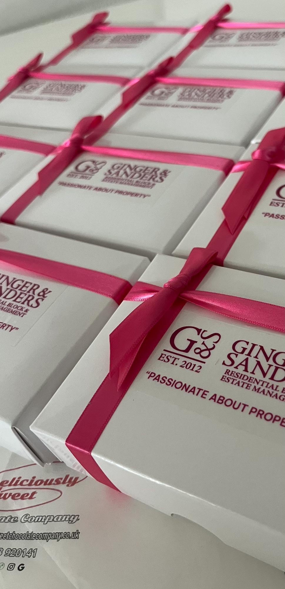 White gift boxes wrapped with bright pink ribbons arranged in rows.