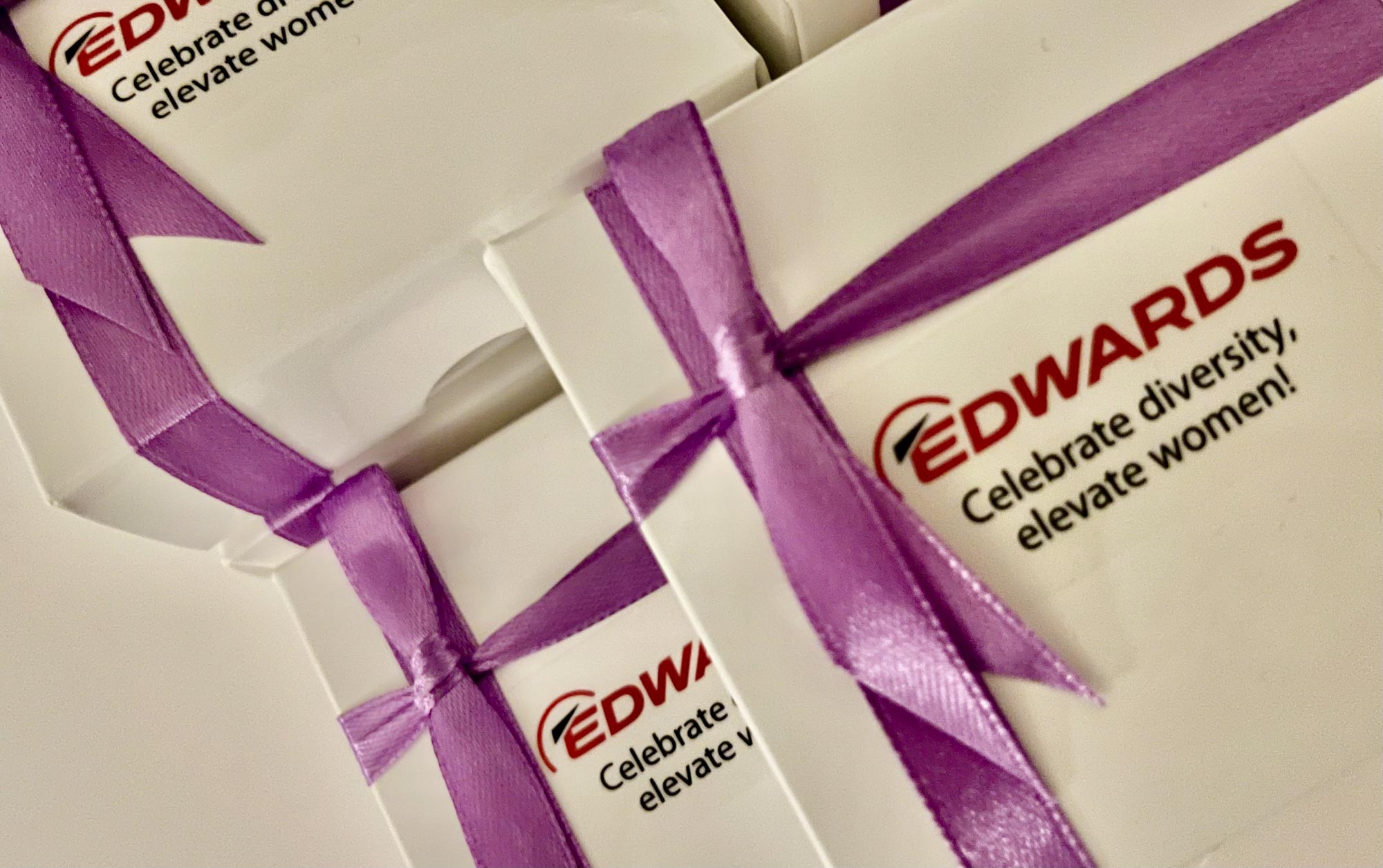 Gift boxes with purple ribbons and a logo reading "EDWARDS: Celebrate diversity, elevate women."