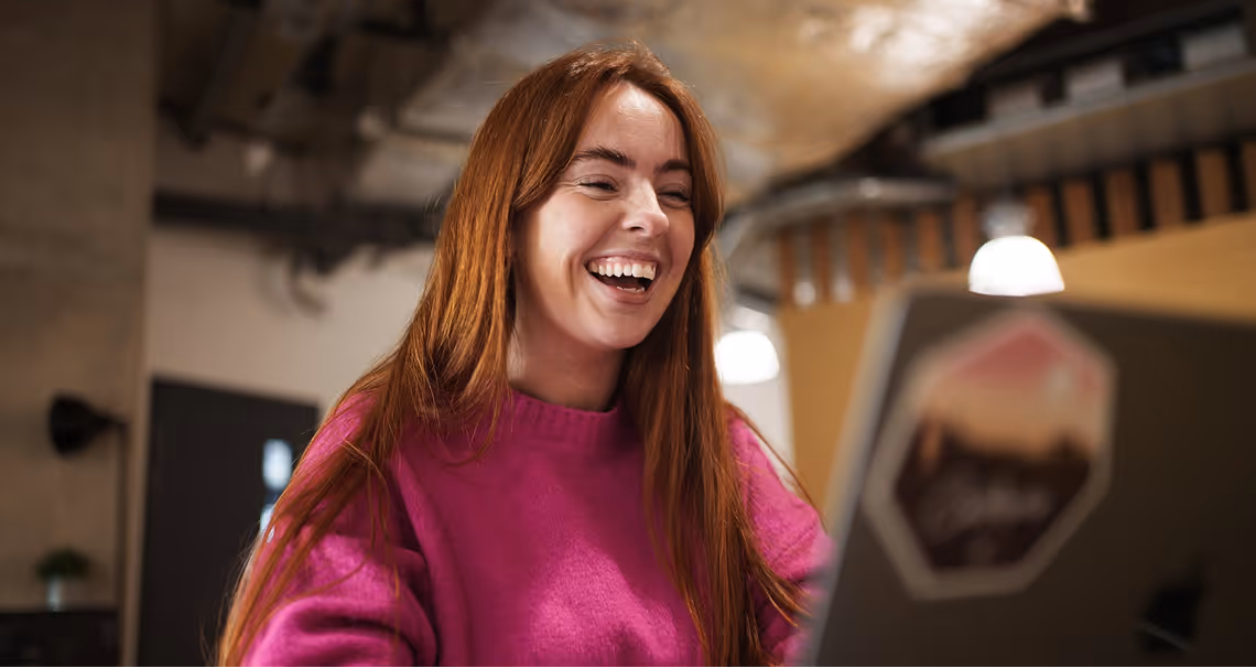 Person smiling while using a laptop