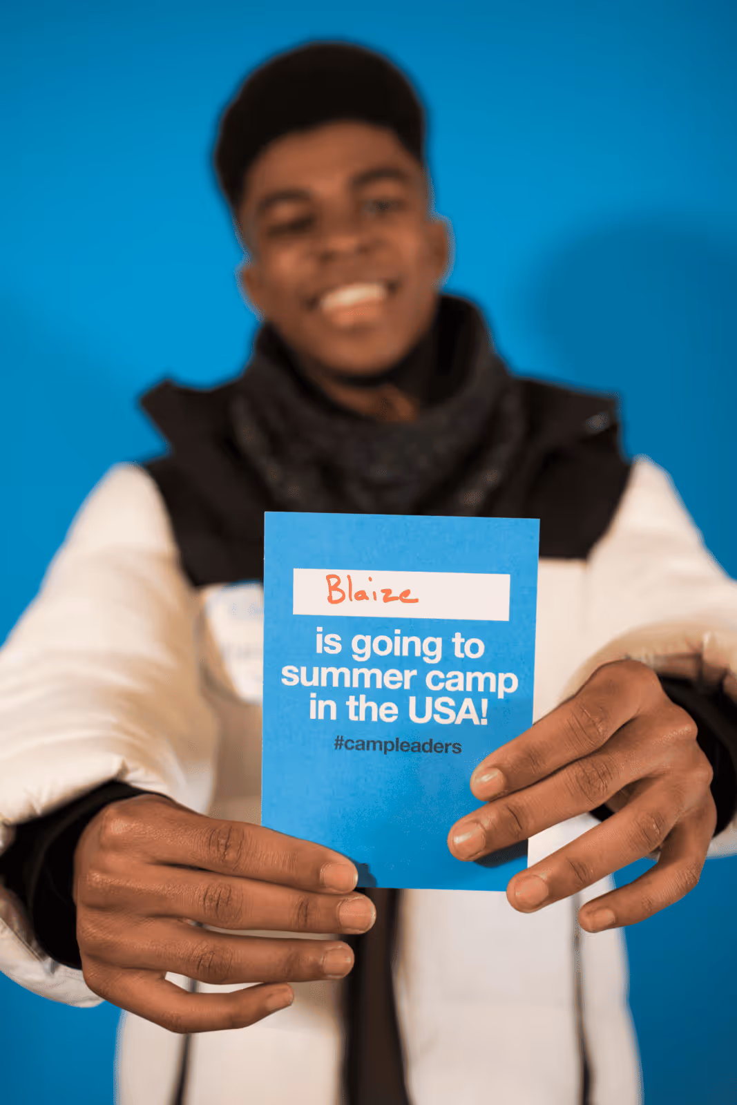 A participant smiling, holding a sign indicating he got hired for a job at a summer camp