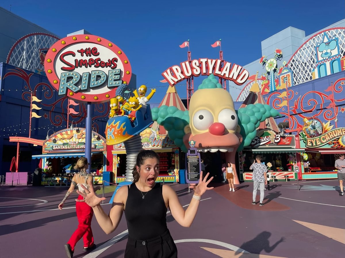 A girl acting surprised in front of a Simpsons theme park