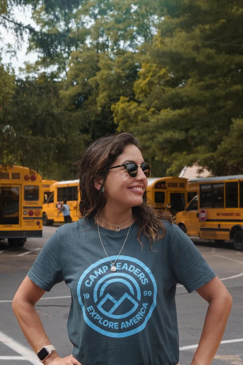 A woman at camp smiling wearing a Camp Leaders tshirt