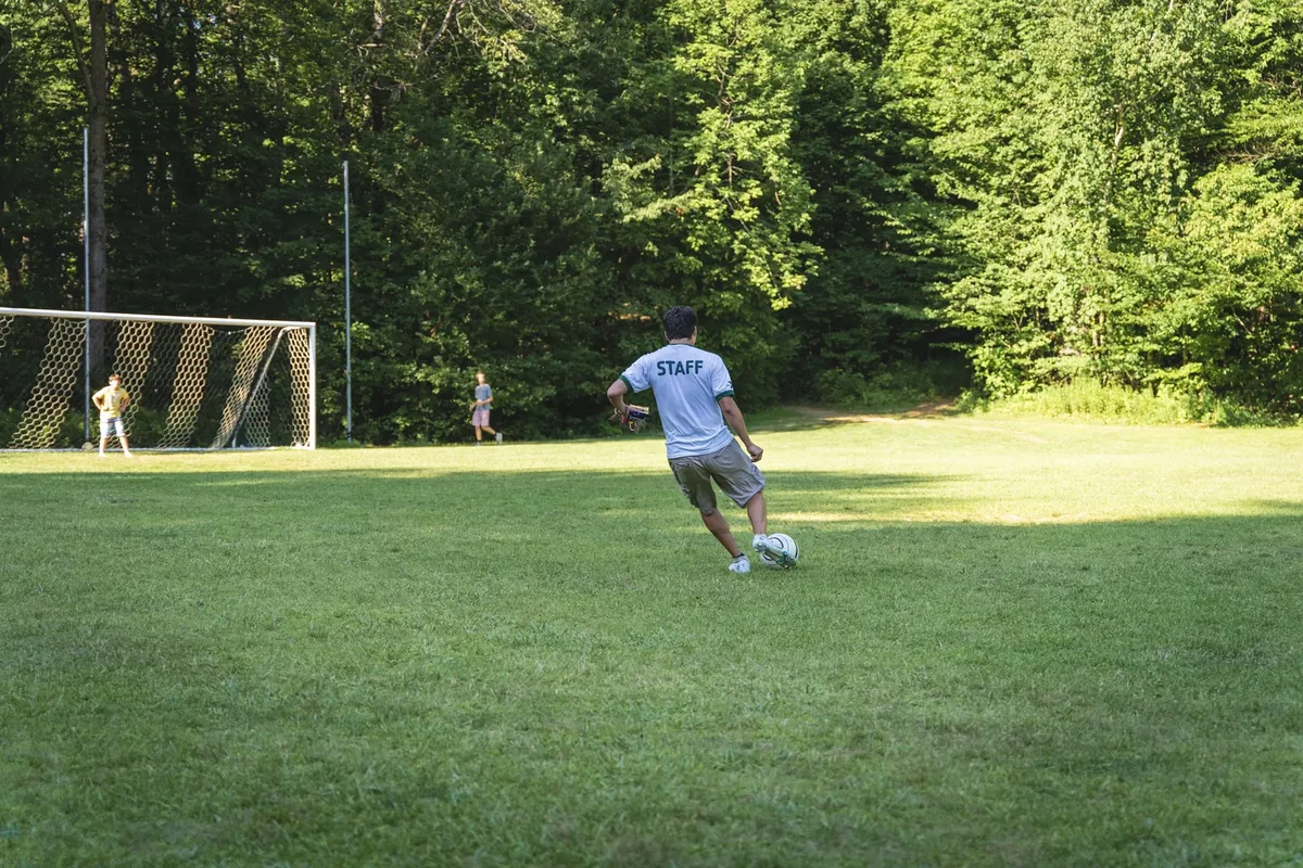 A counselor playing football with campers