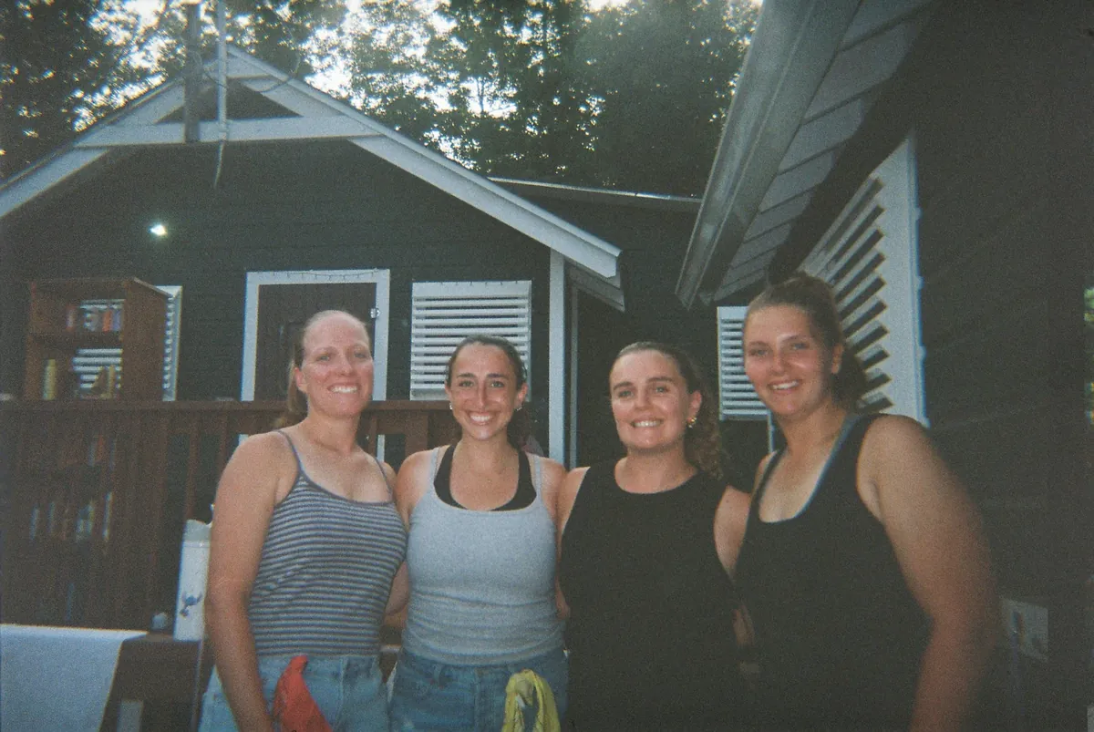 Four counselors smiling outside a camp cabin