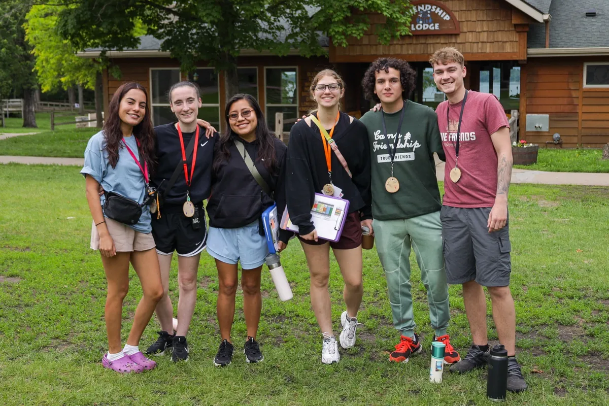Camp Leaders counselors with medals outside a camp lodge
