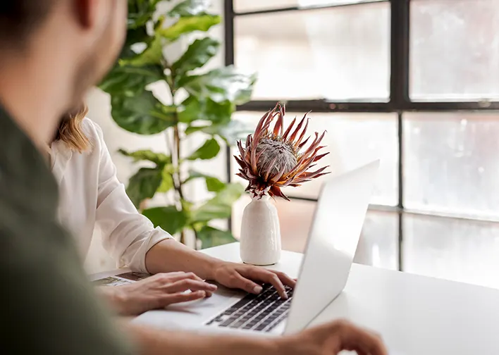 two people work at a laptop computer in a well lit office space