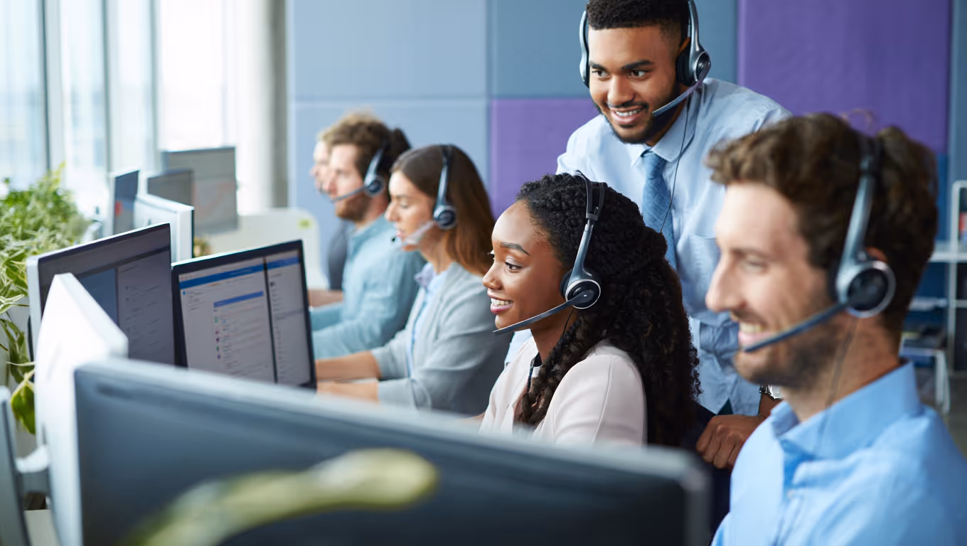 Équipe diversifiée de téléconseillers casqués dans un open space lumineux gérant les appels d'un centre d'appels moderne