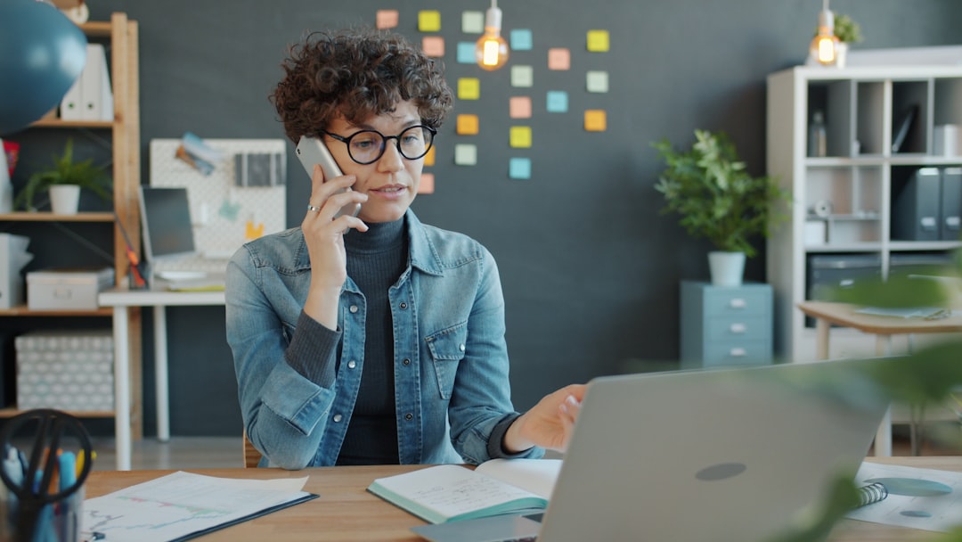 Woman talking on phone at desk with laptop. for How to Optimize Your Google Business Profile for Local Search Rankings