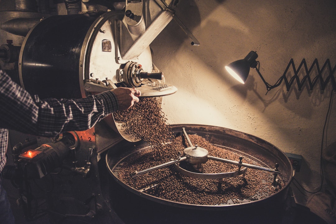 Person pouring coffee beans on a machine for How a Local Coffee Roastery Increased Online Orders by 240% Through Strategic Website Redesign and User Experience Improvements