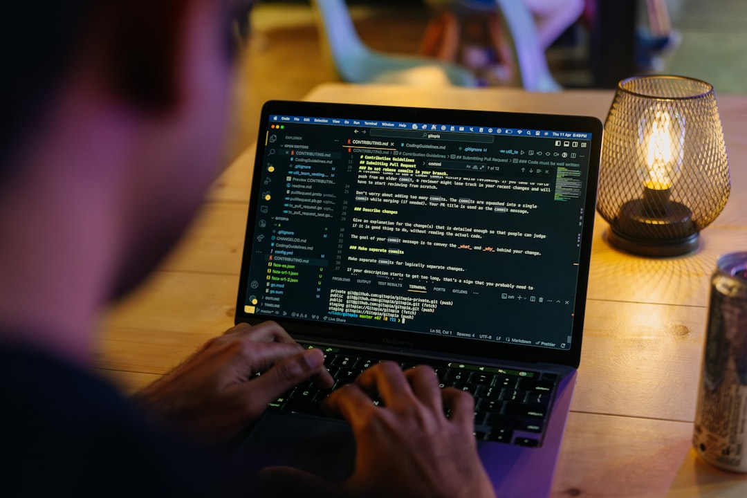 A person sitting at a table with a laptop for How to Choose Between React, Vue, and Angular for Your Small Business Website