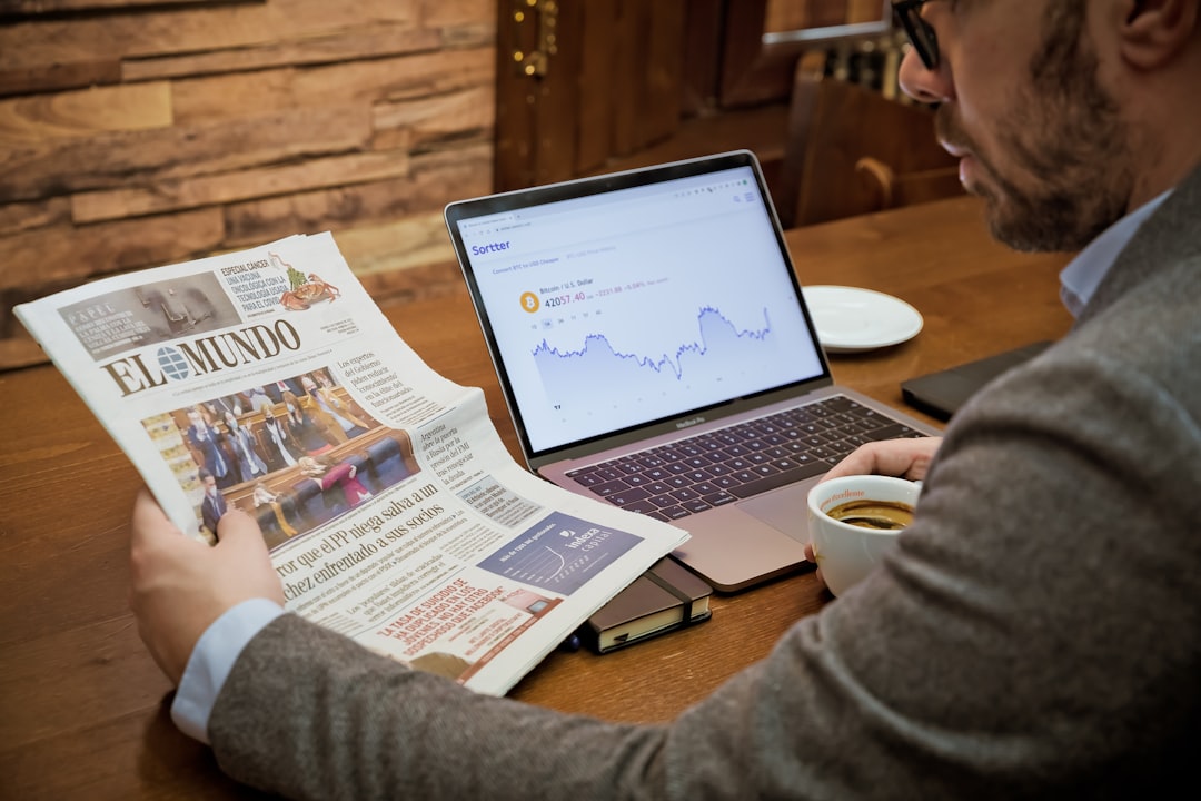 A man reading a newspaper while using a laptop for How to Find Low-Competition Keywords Your Small Business Can Actually Rank For