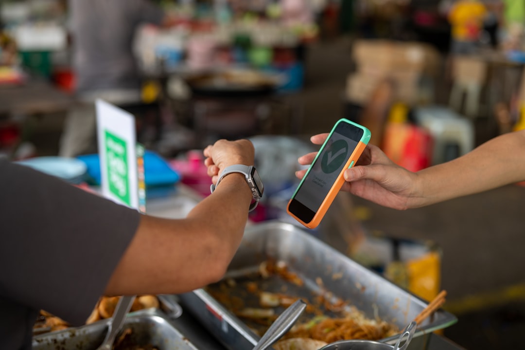 A person handing another person a cell phone for How to Design Mobile-First Checkout Experiences That Reduce Cart Abandonment