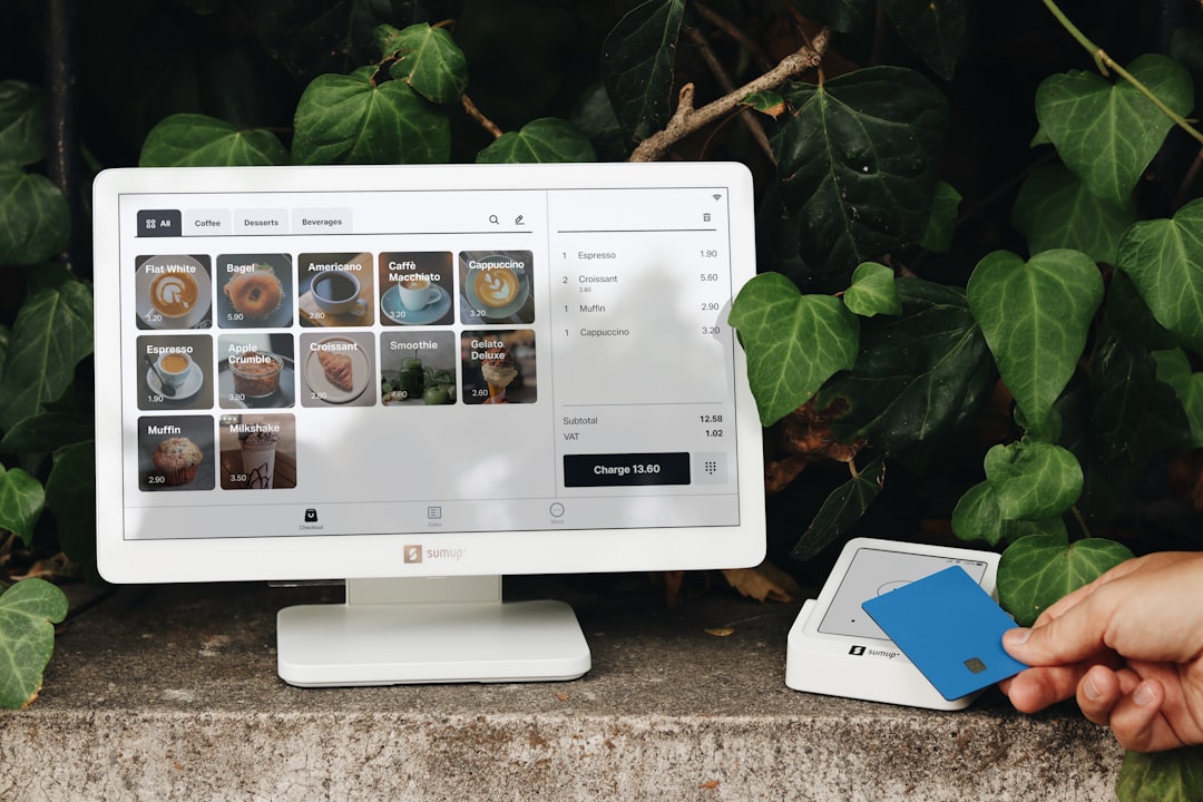 A person holding a blue card in front of a computer for How to Design Mobile-First Checkout Experiences That Reduce Cart Abandonment