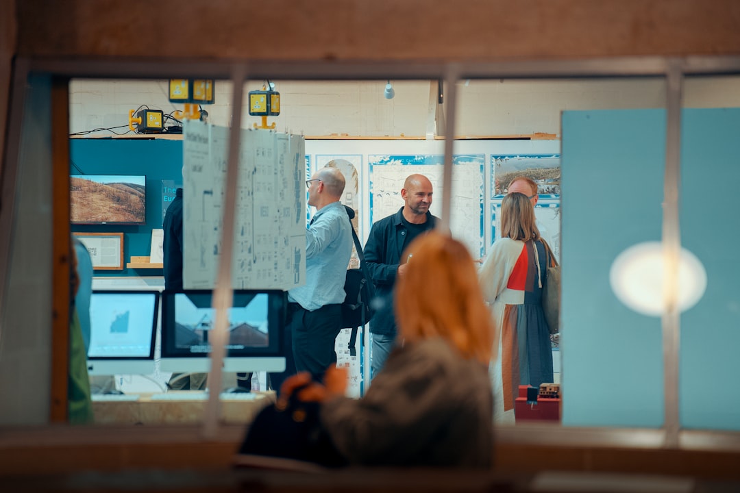 People conversing in an office, viewed through a window. for "How to Modernize Your Website Without Losing Customer Trust: A Step-by-Step Redesign Strategy"