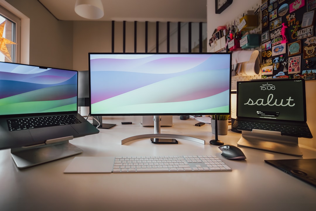 A desk with three computer monitors and a keyboard for "How to Modernize Your Website Without Losing Customer Trust: A Step-by-Step Redesign Strategy"