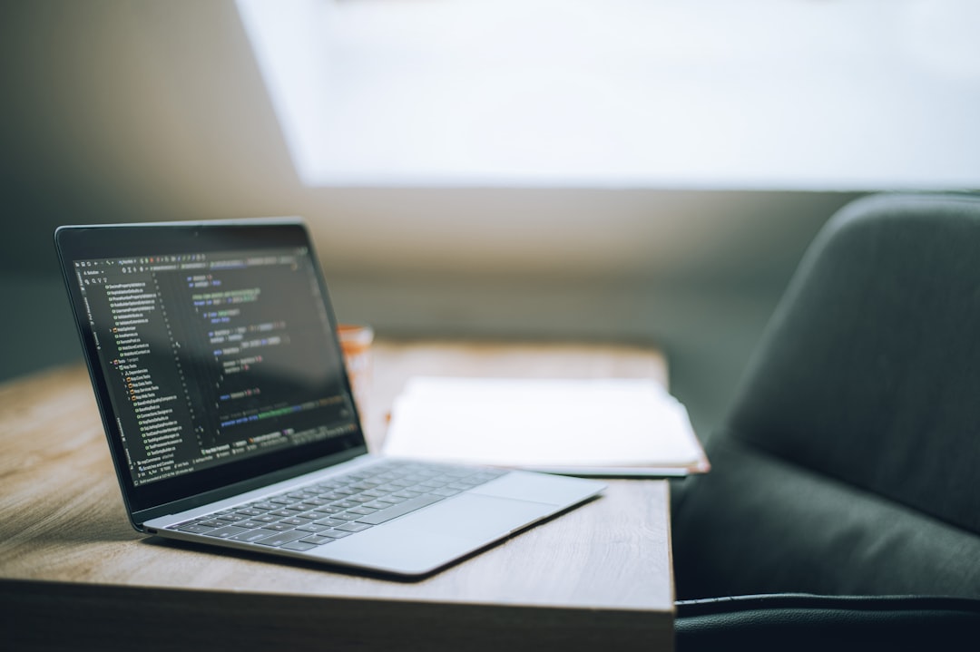 Laptop displaying code on a wooden table for How to Choose Between React, Vue, and Angular for Your Small Business Website