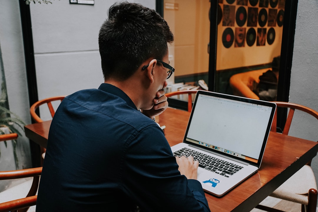 A man sitting at a table using a laptop computer for The Complete Guide to Finding Long-Tail Keywords Your Small Business Competitors Are Missing
