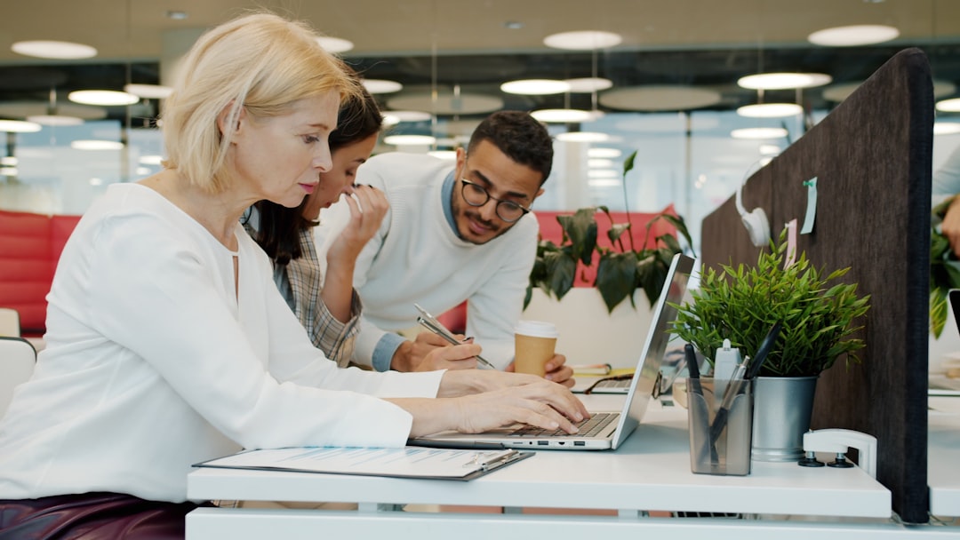 Three people working together on a laptop for "The Complete Guide to Choosing the Right Figma Plan for Your Small Business Website Project"